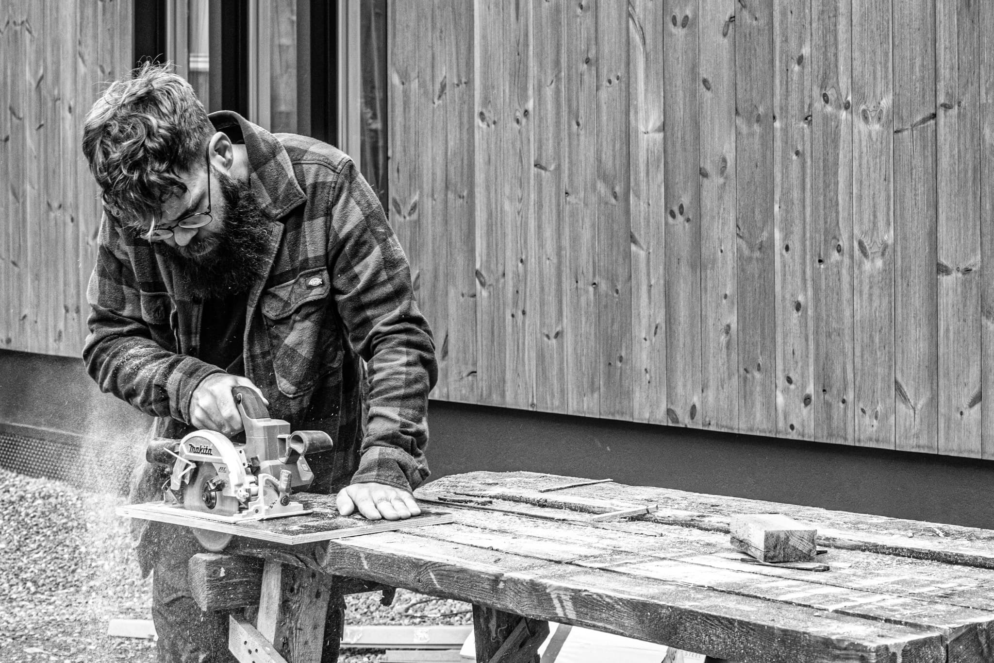 Rakennustyöntekijä sirkkelöi lautaa ulkona Makita-sirkkelillä